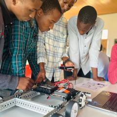 Rwandan students huddled around robot